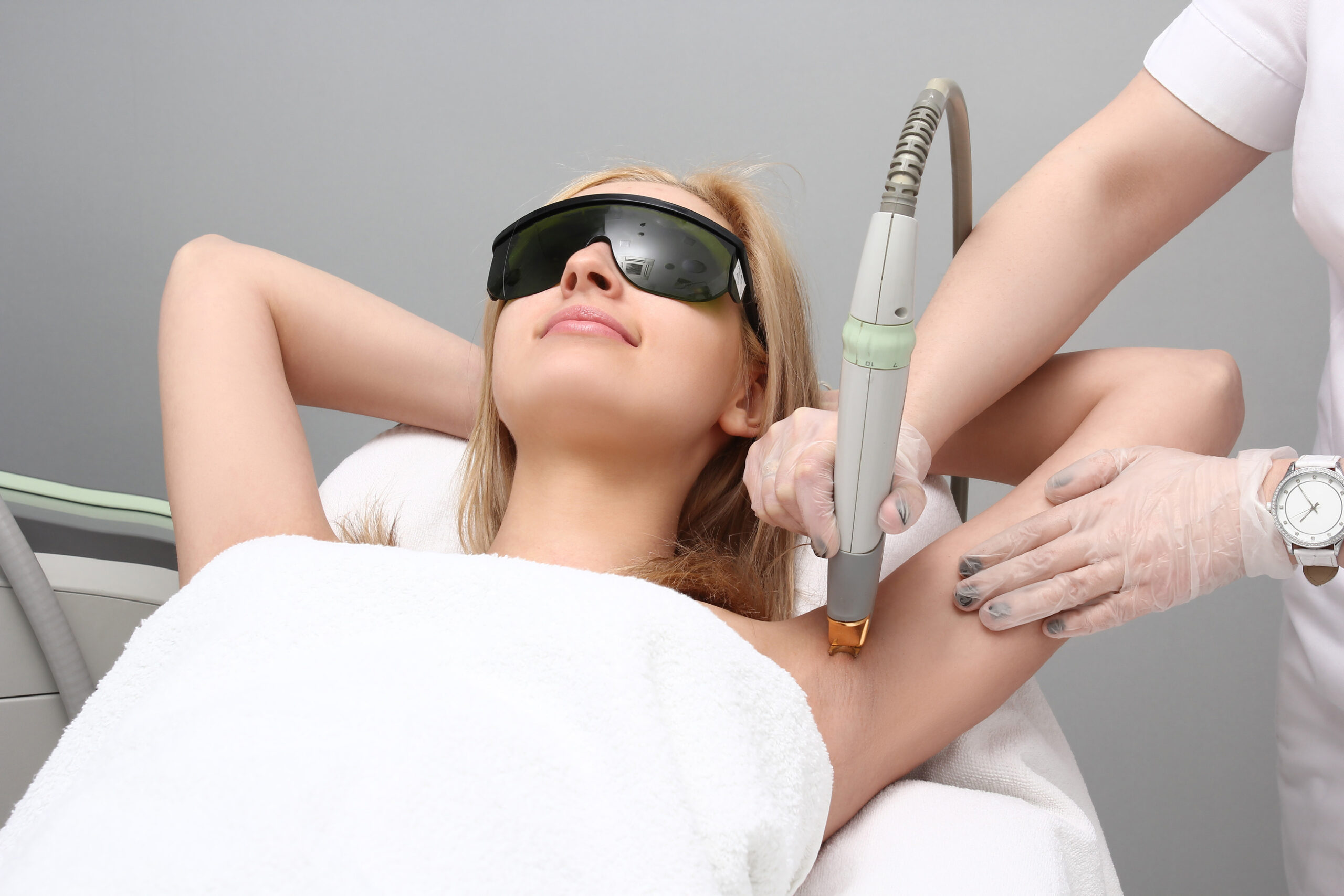 Blonde woman having underarm Laser hair removal epilation. Laser treatment.