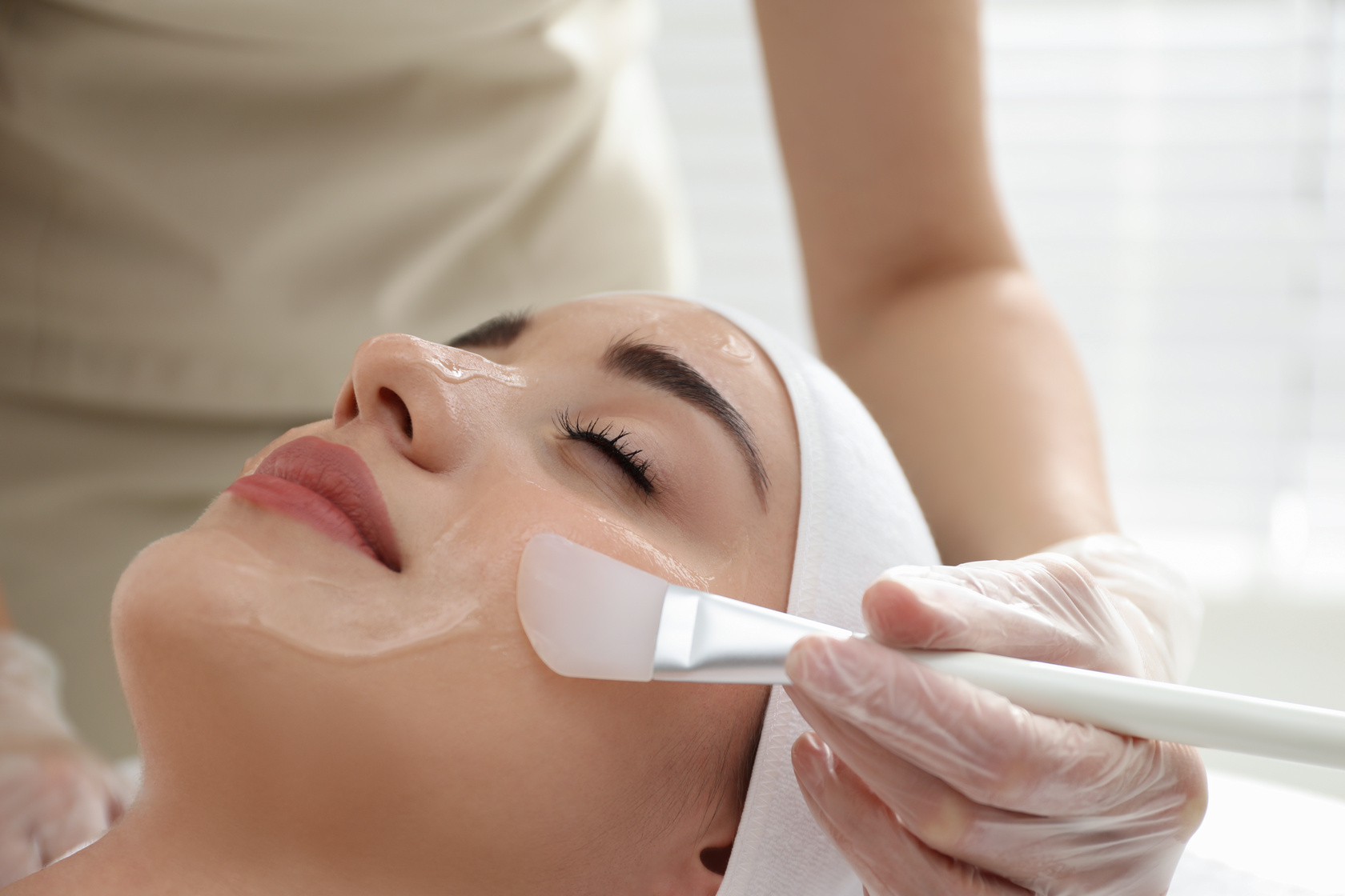 Young woman during face chemical peeling procedure in salon